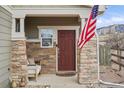 Inviting front porch features stone columns and cozy seating with an American flag at 5671 Raleigh Cir, Castle Rock, CO 80104