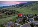 Picturesque aerial view of the property surrounded by green hills, mature trees and a winding neighborhood street at 87 Deerwood Dr, Littleton, CO 80127
