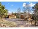 Exterior view of home and detached garage with driveway and natural landscaping at 11648 Broken Arrow Dr, Conifer, CO 80433