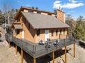Attractive exterior view of raised brown home featuring wraparound deck with seating and mountain views at 11648 Broken Arrow Dr, Conifer, CO 80433