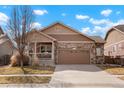 Charming single-Gathering home featuring a stone facade, covered porch, and two-car garage at 5172 Purple Mustard Ct, Brighton, CO 80601