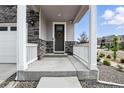 Inviting front porch with stone accents, white railing, and a decorative wreath on the front door at 27504 E 1St Pl, Aurora, CO 80018