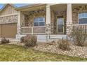 Inviting front porch with stone columns and a view of the well-maintained front yard at 6302 E 135Th Ave, Thornton, CO 80602