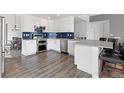 Bright kitchen with stainless steel appliances, white cabinetry, and a blue tiled backsplash at 3656 E 134Th Dr, Thornton, CO 80241