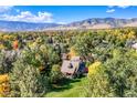 An aerial view showcases the property surrounded by lush trees with mountain views in the distance at 3737 26Th St, Boulder, CO 80304