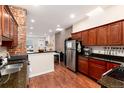 Modern kitchen with stainless steel refrigerator, dark wood cabinets, granite countertops, and exposed brick accents at 3220 W 24Th Ave, Denver, CO 80211