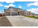 Exterior view of homes with long driveways, landscaped front yards, and attached two-car garages at 13489 Valentia Pl, Thornton, CO 80602