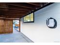Covered carport features electric vehicle charger, horizontal wood slat detail, and access to back yard at 2441 W 55Th Ave, Denver, CO 80221