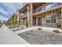 View of townhome exterior with stone accents, wooden beams, and well-kept landscaping at 9662 Browns Peak Cir, Littleton, CO 80125