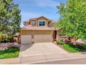 Charming two-story home featuring a large driveway and a well-maintained front yard with mature trees at 2485 Greensborough Cir, Highlands Ranch, CO 80129