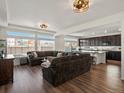 Open-concept living room flows into the kitchen, featuring wood floors, recessed lighting, and large windows at 21901 E 42Nd Pl, Aurora, CO 80019