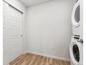 Bright laundry room with a stackable washer and dryer set and wood-look floors at 485 Interlocken Blvd # 106, Broomfield, CO 80021