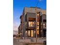 Townhouse featuring a stylish facade with grey brick, dark metal, and cantilevered balcony, enhanced by warm lighting at 2326 Eliot St # 7, Denver, CO 80211