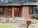 Home's front entrance featuring a wood door with glass panels, brick exterior, and landscaped garden bed at 1 Winged Foot Way, Littleton, CO 80123