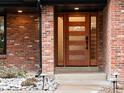 Home's modern front door features horizontal glass panels and brick siding at 1 Winged Foot Way, Littleton, CO 80123