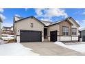 Beige and brown two-story house with dark garage door and snowy landscape at 16850 Mckay Dr, Mead, CO 80542