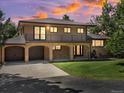 Sunset image of this home featuring a brick facade, covered entryway, two-car garage, and manicured lawn at 12196 W Belleview Dr, Littleton, CO 80127
