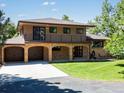 Charming two-story home with a brick facade, spacious driveway, and manicured lawn at 12196 W Belleview Dr, Littleton, CO 80127
