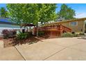 This backyard view showcases a lush lawn, mature trees, a spacious wooden deck, and a charming pergola at 5573 S Datura St, Littleton, CO 80120