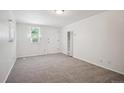 Clean and bright living room with neutral carpet, fresh paint, and an exterior access door at 5549 S Greenwood St, Littleton, CO 80120