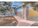 Close-up of a two-story home with a stone facade, walkway, and a vibrant yellow garage door at 4027 Hawthorne Cir, Longmont, CO 80503