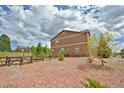 A house with neutral siding, surrounded by a stone yard with a wood rail fence at 735 Woodmoor Acres Dr, Monument, CO 80132