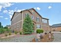 Two-story home with stone accents and a lush tree in front of an arched entryway and three car garage at 735 Woodmoor Acres Dr, Monument, CO 80132