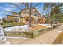 Two-story home with tan siding, brick accents, and landscaped front yard with retaining wall and bare trees at 8747 E Dry Creek Rd # 1623, Englewood, CO 80112