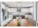 Open kitchen features white cabinets, stainless appliances, and a central island with pendant lighting at 11584 Pine Canyon Ln, Parker, CO 80138