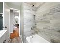 Updated bathroom with marble-look tile, soaking tub, and modern fixtures at 2955 Poplar St, Denver, CO 80207