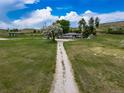 Long gravel driveway leads to a charming home with mature trees and lots of green grass at 14831 Riverdale Rd, Brighton, CO 80602