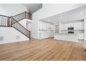 Open-concept living space featuring a staircase, hardwood floors, and a modern kitchen with white cabinetry at 16671 W 93Rd Ave, Arvada, CO 80007