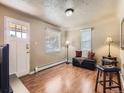 Bright living room featuring wood floors, two windows with blinds, and a white door at 3265 S Ogden St, Englewood, CO 80113