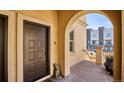 Brown front door with an arched entryway and concrete front porch with views of neighboring townhomes at 150 S Harrison St # 9, Denver, CO 80209