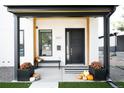 Inviting covered porch with a modern black door, bench, and seasonal decor for a cozy curb appeal at 2321 S Acoma St, Denver, CO 80223