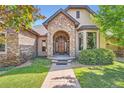 Charming front entrance with a stone archway and custom wood door provides inviting curb appeal at 4725 Palmer Ridge Dr, Parker, CO 80134