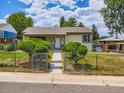 Inviting home featuring a fenced yard with an open gate and manicured shrubbery at 235 S Stuart St, Denver, CO 80219