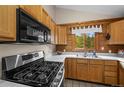 Well-lit kitchen features stainless steel appliances, wooden cabinets, and a bright window overlooking trees at 310 Wendelyn Way, Boulder, CO 80302