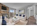 Bright, staged living room with hardwood floors, stone fireplace, and sliding glass doors to balcony at 4460 S Pitkin St # 120, Aurora, CO 80015