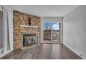 Bright living room with hardwood floors, stone fireplace, and sliding glass doors to balcony at 4460 S Pitkin St # 120, Aurora, CO 80015