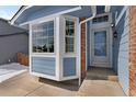 Close-up of the front entryway, highlighting the bay window, blue siding, and brick detail at 13151 Ivanhoe St, Thornton, CO 80602