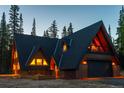 Exterior view of an A-frame home with wood accents and black roof, illuminated at dusk surrounded by trees at 297 Robertson Ln, Breckenridge, CO 80424