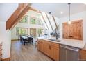 A-frame living area featuring exposed beams, wood floors, fireplace, dining table, and access to kitchen at 297 Robertson Ln, Breckenridge, CO 80424