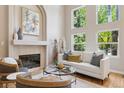 Bright living room featuring a fireplace, tall windows offering views of lush greenery, and a cozy seating arrangement at 6393 S Jamaica Ct, Englewood, CO 80111