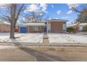 Ranch style home with a blue garage door and snowy yard at 12352 E 30Th Ave, Aurora, CO 80011