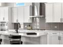 Bright kitchen featuring white cabinets, subway tile backsplash, and stainless steel vent hood at 5597 Pinto Valley St, Parker, CO 80134