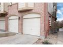 Attached garages for townhouse, featuring individual doors and brick facade details at 341 Granby Way # A, Aurora, CO 80011