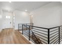 Bright hallway with wood floors, metal railing, a white door, and recessed lighting at 8658 Pennycress Dr, Littleton, CO 80125