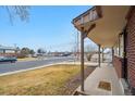 Cozy covered porch with brick supports providing a comfortable outdoor space with a view of the neighborhood at 3261 Kassler Pl, Westminster, CO 80031