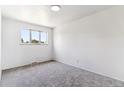 An empty carpeted bedroom with neutral walls and bright natural light from a large window at 370 S Parfet St, Lakewood, CO 80226
